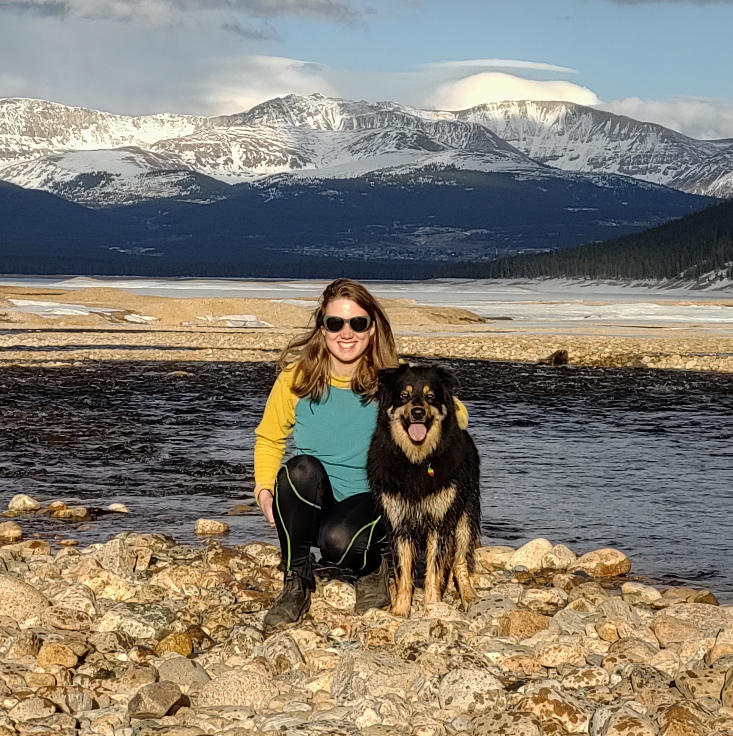 Mary with her dog sitting in front of mountain range.